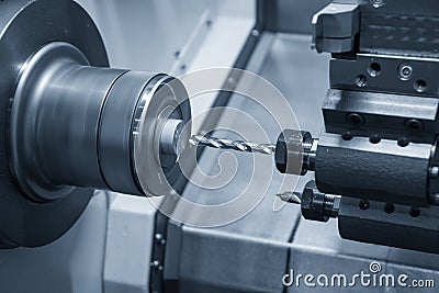 The CNC lathe machine drill cutting the metal shaft parts Stock Photo