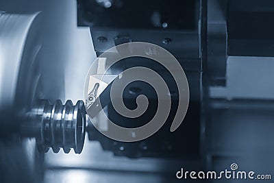 The CNC lathe machine in metal working process cutting the groove at the pulley parts with the cutting tools. Stock Photo