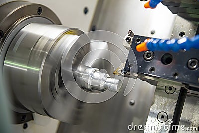 The CNC lathe machine in metal working process cutting thread the metal shaft parts with in the light blue scene. Stock Photo