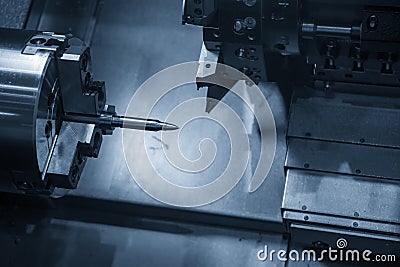 The CNC lathe machine operation by cutting the sample bullets parts in the light blue scene. Stock Photo