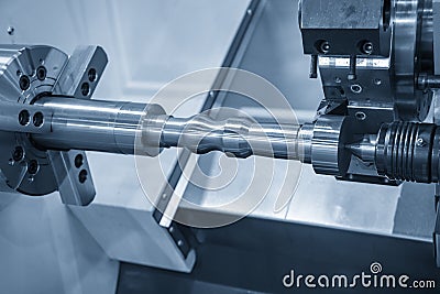 The CNC lathe machine rough cutting the metal shaft parts with cutting tools for make the automotive parts. Stock Photo