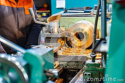 A cnc lathe worker makes a round piece of bronze Stock Photo