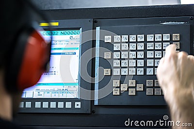 CNC operator, at metal machining milling center in tool workshop inserting data with keyboard wearing Stock Photo
