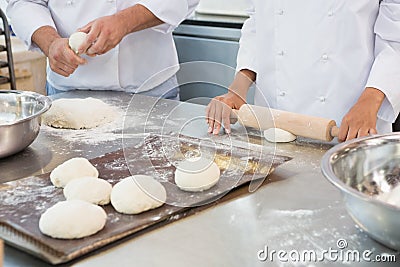 Co-workers kneading uncooked dough together Stock Photo