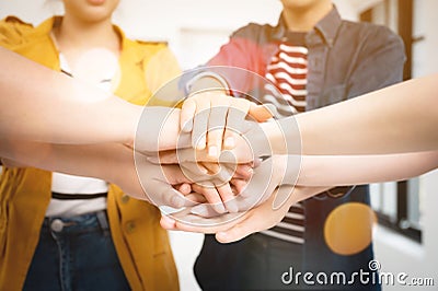 Co-working startup business team and teamwork concept. Young team putting hands up in creative office Stock Photo