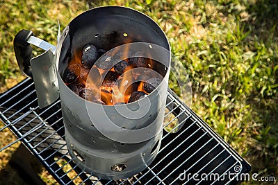 Coal of charcoal grill burning in flames with fire and lighter in barbecue chimney for BBQ evening Stock Photo