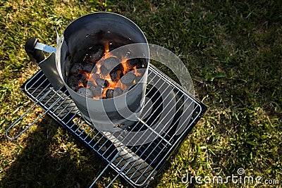 Coal of charcoal grill burning in flames with fire and lighter in barbecue chimney for BBQ evening Stock Photo
