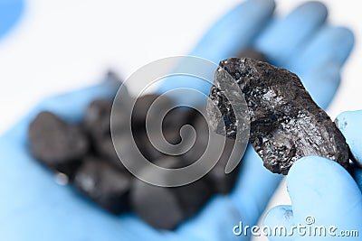 Coal lump in scientist hand and small heap in other. Stock Photo
