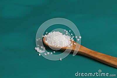 Coarse salt crystals on a blue table. Wooden spoon with sea salt. Stock Photo