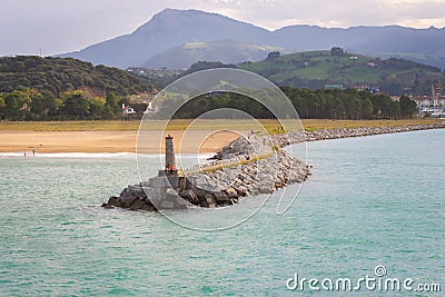 Coast with lighthouse and moor with town and mountains on background. Biscayne bay with scenic coastline. Stock Photo