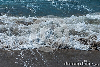 Coast of Mediterranean Sea in Fethiye, Turkey. Turquoise foamy waves run to the sand beach. Close-up Stock Photo
