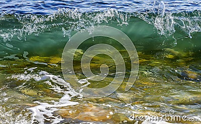 Coastal transparent sea/ocean crashing wave with foam on its top Stock Photo