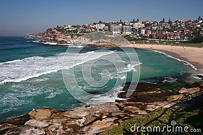 Idyllic and amazing seaside landscape of jagged shore with rocks, white rushing sea waves, hillside buildings in Sydney, Australia Stock Photo