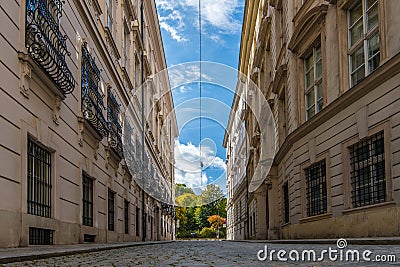 A cobbled Viennese street near to the university, with white clouds and blue sky above. Street light cables run through the frame Stock Photo
