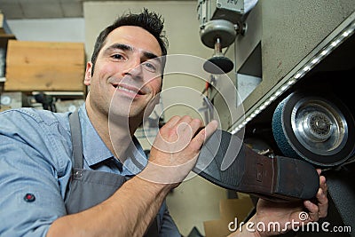 cobbler holding heel shoe against rotating wheel Stock Photo