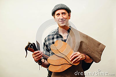 Cobbler holding set of tools and leather. Shoemaker modeling mens shoe at his workshop. Small business concept. Handmade leather Stock Photo