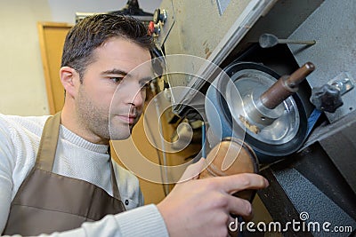 Cobbler holding sole shoe against rotating wheel Stock Photo