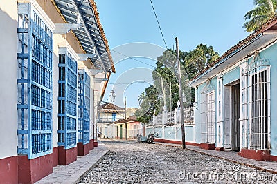 Cobblestone street with coloured buildings, wooden window bars in colonial old town Trinidad, Cuba Stock Photo