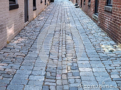 Cobblestone street in the daytime moving through a brick alleyway Stock Photo