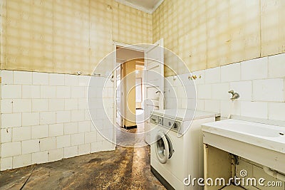 Cocina vieja, sucia y destartalada con suelo oscuro, azulejos blancos y papel amarillo en las paredes Stock Photo