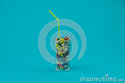 Cocktail of drugs in a glass on a blue background, the concept of uncontrolled drug use Stock Photo