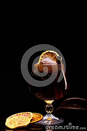 Cocktail with ice cube, lemon and cinnamon stick in a glass on a black background Stock Photo