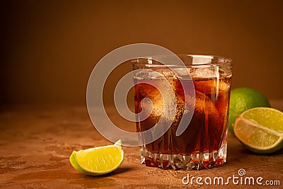 Cocktail from rum ice cubes and lime in glass goblet on a dark brown background. Strong alcoholic drink. Copy space. Stock Photo