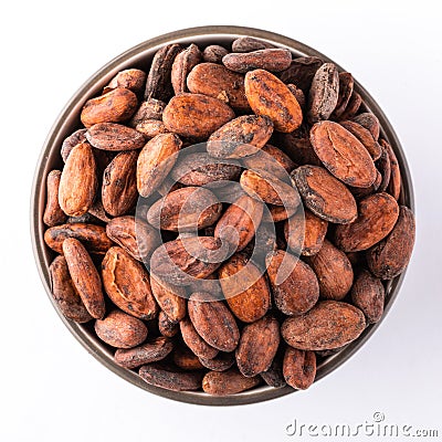 Cocoa beans in a round bowl on white background, top view. Vegan food ingredients Stock Photo