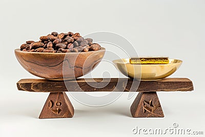 Cocoa beans in a wooden bowl and golden spoon on a wooden stand isolated on white background Stock Photo