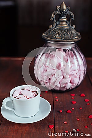 Cocoa drink with marshmallows and glass vintage retro jar with pink candy on wooden table Stock Photo