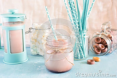 Cocoa in a jar of straw. In the background, a blue coffee pot, marshmallows and turquoise cocktail tubes in a blur. A Stock Photo