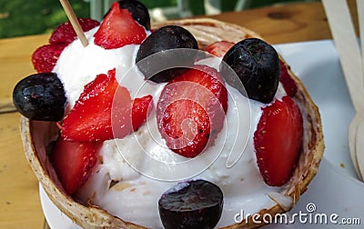 coconut ice-cream in coconut with strawberries and chocolate chips as topping Stock Photo