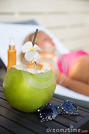 Coconut juice drink with woman on lounger near a swimming pool Stock Photo