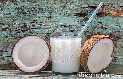 Coconut milk and fresh and halved coconuts on wooden table Stock Photo