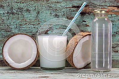 Coconut milk and fresh and halved coconuts on wooden table Stock Photo