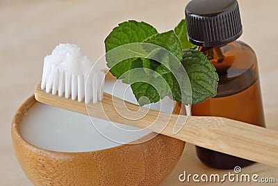 Coconut oil in a bowl with a wooden toothbrush and peppermint essential oil - Homemade natural toothpaste Stock Photo