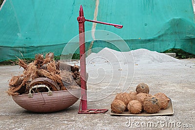 Coconut peeling machine with peeled coconut on one side and the dry husks leftover after peeling on the other side filled in a Stock Photo