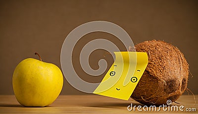 Coconut with post-it note looking at apple Stock Photo