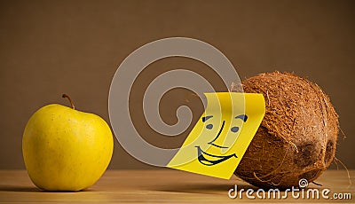 Coconut with post-it note smiling at apple Stock Photo