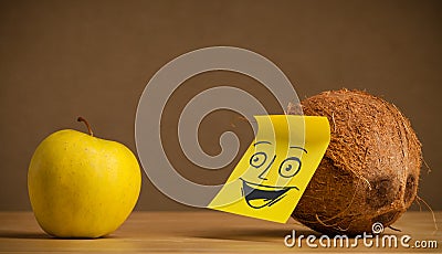 Coconut with post-it note smiling at apple Stock Photo