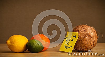 Coconut with post-it note smiling at citrus fruits Stock Photo