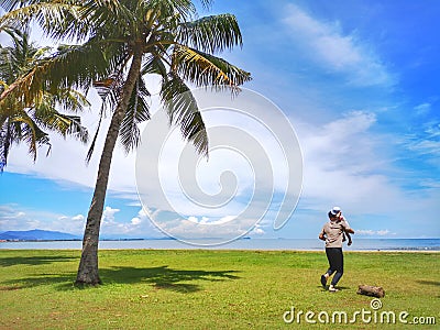 A family outing and coconut tree on the Tanjung Aru Beach, Kota Kinabalu with the beautiful blue sky above on sunny day. Editorial Stock Photo
