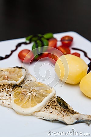 Cod fish dish with lemons and tomatoes Stock Photo