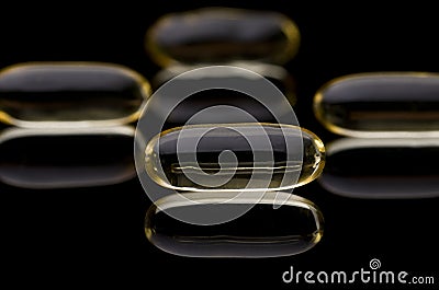 Cod liver vitamin D capsules on black reflective surface Stock Photo