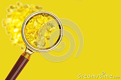 Cod liver vitamin E capsules seen through a magnifying glass. Stock Photo