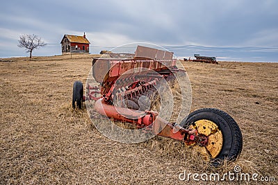 Coderre, SK- April 9, 2020: Vintage Massey-Ferguson discer abandoned in a pasture with a weathered farmhouse in Saskatch Stock Photo