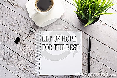 Cofee cup, notepad,pen on the wooden background. Business concept. Text LET US HOPE FOR THE BEST Stock Photo
