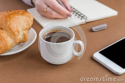 Coffe break with croissant and espress. Woman writing on notebook . Freelancer at work Stock Photo