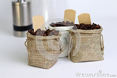 Coffee beans in burlap bags with blank labels on white background. Stock Photo