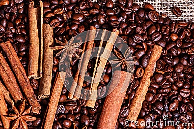 Coffee beans and cinnamon on a background of burlap. Roasted coffee beans background close up. Coffee beans pile from top with cop Stock Photo